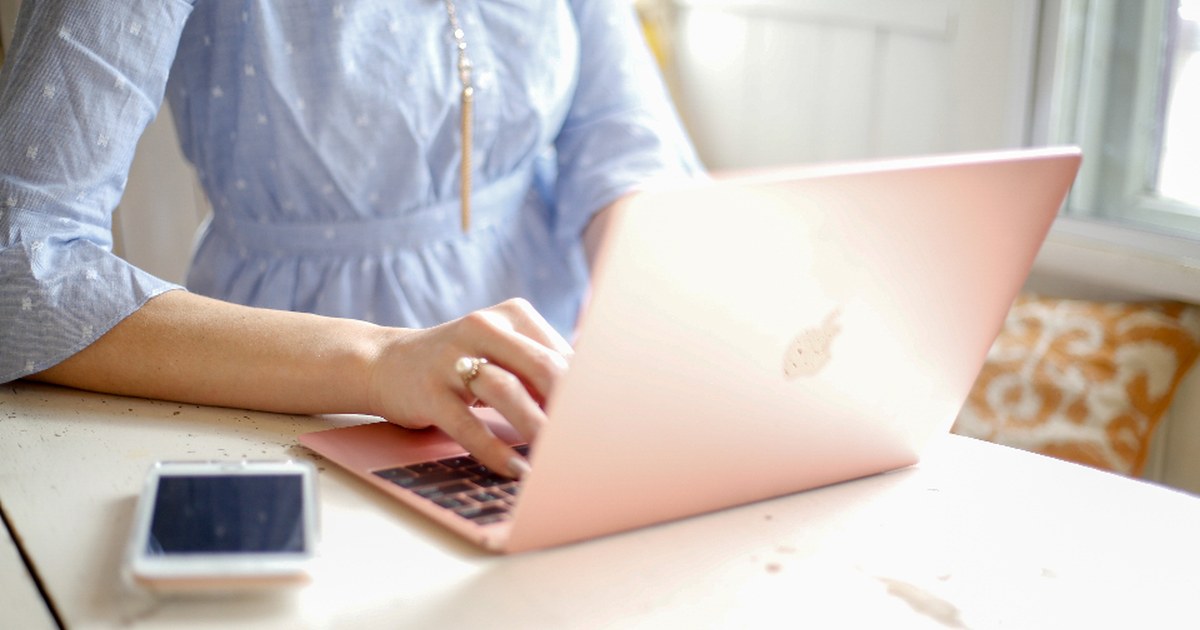 Person using a laptop and smartphone at a bright desk, illustrating online casino identity verification and payment checks