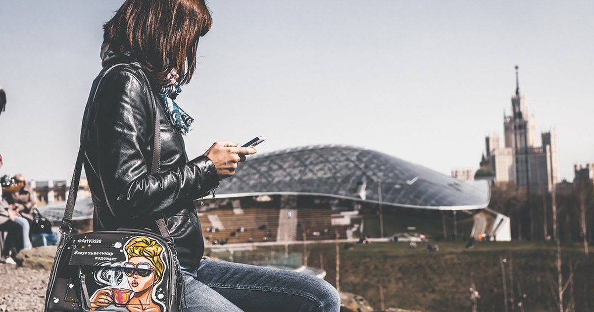 A woman using a smartphone outdoors in a city, illustrating online casino play on mobile devices.