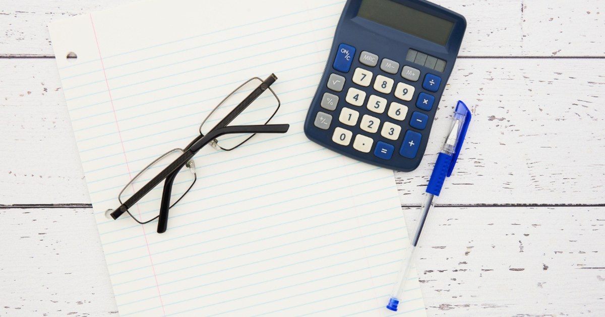 Calculator, glasses and paperwork on a white desk, illustrating financial checks for online casino players