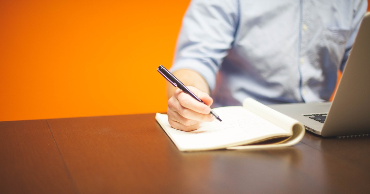 Person taking notes beside a laptop while researching online slot rules.