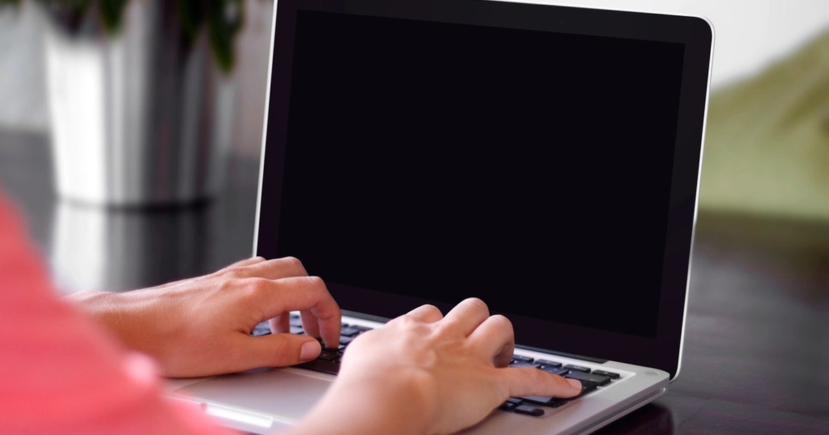 Person typing on a laptop at a desk while using an online account