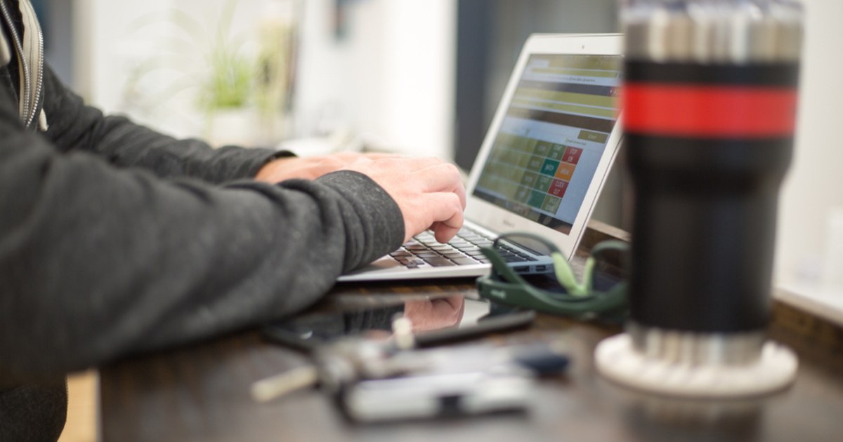 Person playing online slots on a smartphone at a desk with a laptop, illustrating Finland online slot tax changes