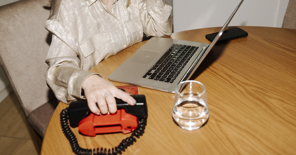 Person using a laptop at a desk with a smartphone and a glass of water