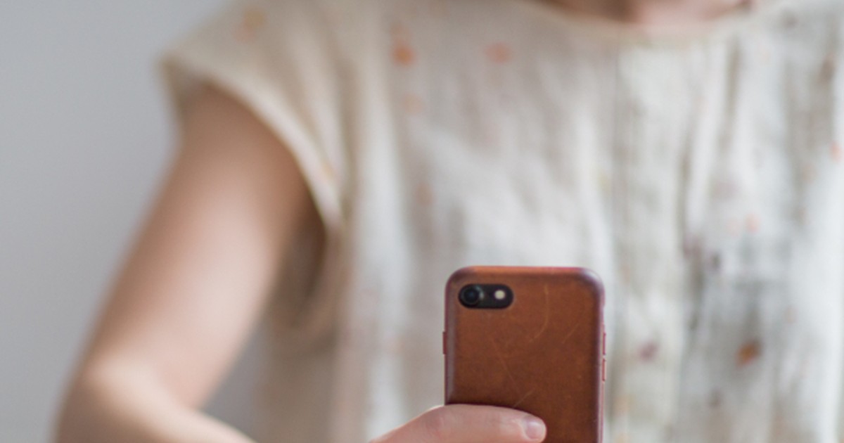 Person holding a smartphone at a desk while managing an online account