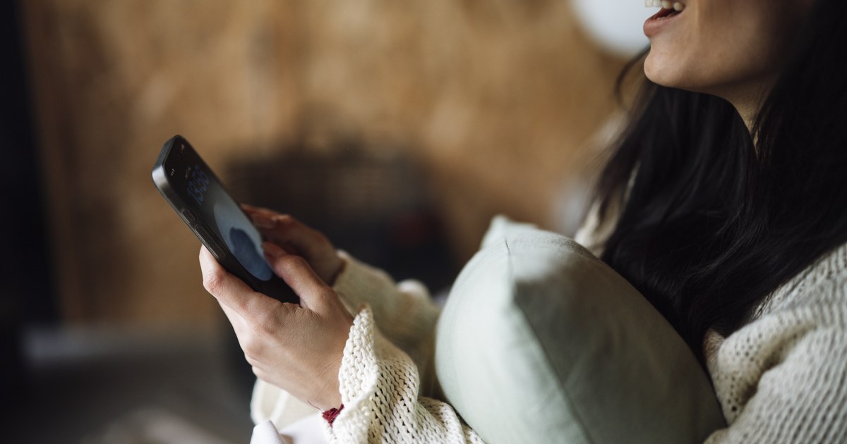 Woman relaxing on a sofa at home using her smartphone