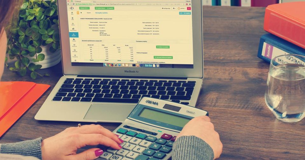 Person using a calculator next to a laptop with financial figures, representing rising casino licence costs