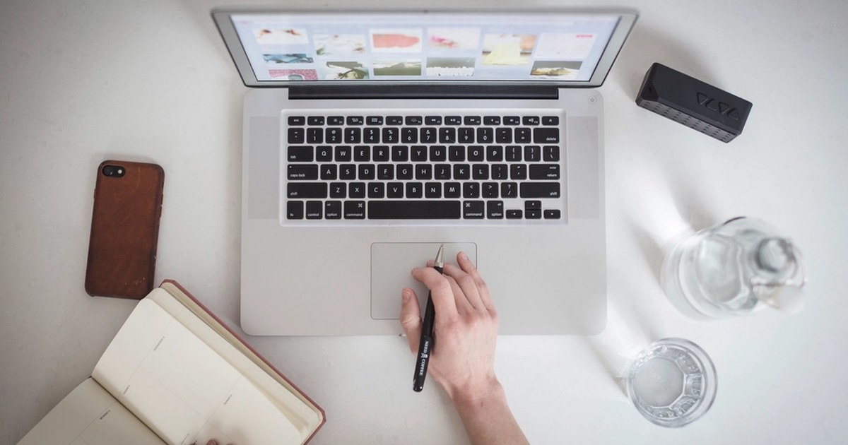 Person at a desk using a laptop and smartphone to browse online